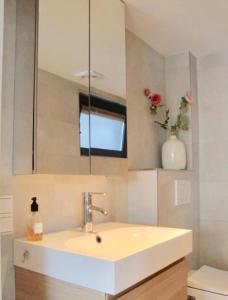 a bathroom with a sink and a vase of flowers at White Sand Beach in Bergen aan Zee
