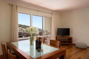a living room with a table with flowers and a television at Apartamento Vale e Mar in Calheta