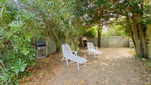 two chairs and a grill in a yard with trees at location proche des plages in Sainte-Marie-de-Ré