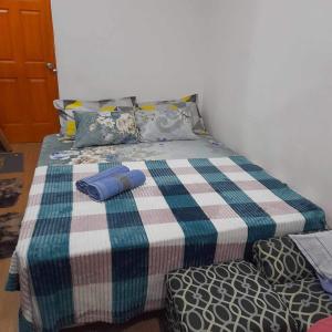 a bed with a plaid blanket and pillows on it at CJ’sstaycation in Lapu Lapu in Maribago