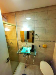 La salle de bains est pourvue d'un lavabo, de toilettes et d'un miroir. dans l'établissement Aluguel Temporada Tramandai Proximo à Praia, à Tramandaí