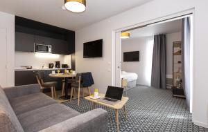 een woonkamer met een bank en een tafel met een laptop bij Odalys City Le Havre Centre Les Docks in Le Havre