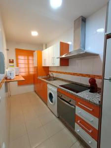 een keuken met oranje en witte kasten en een fornuis bij apartamento Castilla in Almodóvar del Río