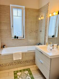 een badkamer met een bad, een wastafel en een spiegel bij MVS Apartment in Giroc