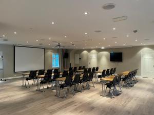 a conference room with tables and chairs and a screen at Hotel Lyngørporten in Gjeving