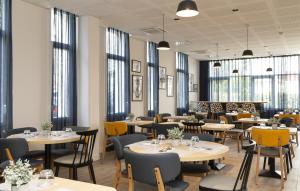 un ristorante con tavoli, sedie e finestre di Odalys City Le Havre Centre Les Docks a Le Havre