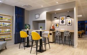 a bar with yellow stools in a room at Appart'hôtel Odalys City - Le Havre Centre Les Docks in Le Havre