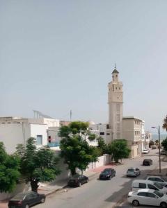 a street with cars parked in front of a clock tower at Grand appart. Carthage Salammbô in Tunis