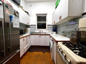 cocina con armarios blancos y nevera de acero inoxidable en Zion, en Sídney