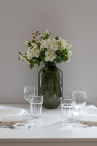 a vase filled with white flowers on a table with glasses at Bright & Comfortable Apartment Garbary 35 Poznań Old Town by Renters in Poznań