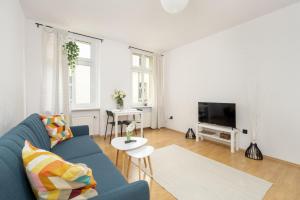 a living room with a blue couch and a tv at Bright & Comfortable Apartment Garbary 35 Poznań Old Town by Renters in Poznań