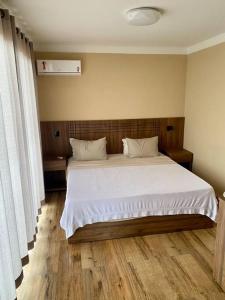 a bedroom with a large bed with white sheets at Vila Germânia, Casa Berlim in Pirenópolis