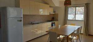 a kitchen with a table and a white refrigerator at Kasa n'areia, Praia Estoril in Sal Rei