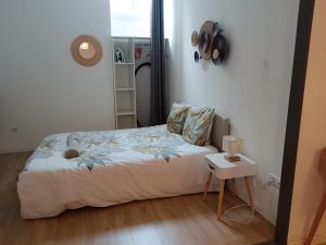 a small bedroom with a bed and a table at Au Cosy Branché in Coudekerque-Branche