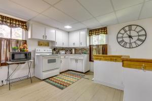 uma cozinha com armários brancos e um relógio na parede em Corning Vacation Rental with Private Fire Pit! 