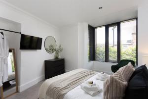 a white bedroom with a bed and a tv at London Mews, modern apartment - sleeps 4 in York
