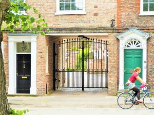una mujer montando una bicicleta delante de una puerta en George Hudson Court Apartments, en York