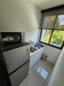 a small kitchen with a microwave on top of a refrigerator at Aya Residence Garden View in Ban Ket Ho