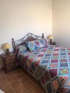 1 cama con un edredón colorido y 2 mesitas de noche en Casa Carmen Martínez en Moncófar