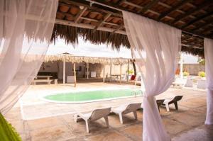 uma vista para uma piscina a partir de um pavilhão com cortinas brancas em Pousada dunas em Luís Correia
