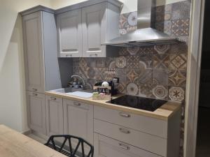 a kitchen with white cabinets and a sink and a stove at La Casa di Dedè monolocale in Sale +2 photos