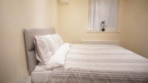 uma cama branca num quarto com uma janela em One Bedroom Apartment at Islington em Londres