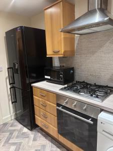 a kitchen with a stove and a black refrigerator at 2 Bed Apartment Sleeps 5, Free Parking, Free Wifi, Spacious, Quiet, Close to Station, Restaurants & Shops, Contractors and Holidays in London