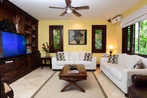 a living room with white couches and a flat screen tv at Afimi Beach House Montego Bay 4BR Beachfront Villa in Montego Bay