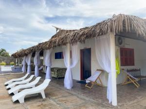 um resort com cadeiras brancas e um telhado de palha em Pousada dunas em Luís Correia