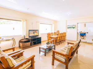 sala de estar con sillas de madera y TV en VELINN Pousada Mirante da Praia Grande, en Ilhabela