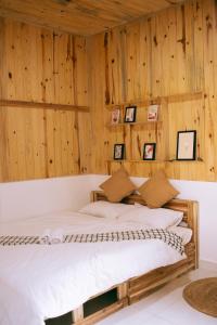 Cama en habitación con paredes de madera en Là Lá La Home en Dalat