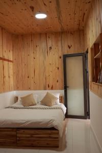 1 dormitorio con 1 cama con pared de madera en Là Lá La Home en Dalat