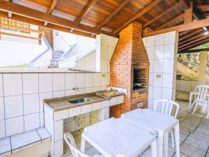 a kitchen with a table and a sink and a fireplace at VELINN Pousada Mirante da Praia Grande in Ilhabela