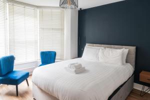 a bedroom with a bed with a hat and two blue chairs at Blue Notes in Westbourne Park in London
