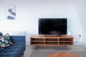 a living room with a blue couch and a flat screen tv at Newly Refurbished 2 bed with Fantastic View in London