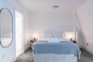 a white bedroom with a bed and a mirror at Newly Refurbished 2 bed with Fantastic View in London