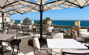 a restaurant with white tables and chairs and the ocean at Grande Real Villa Itália Hotel & Spa in Cascais