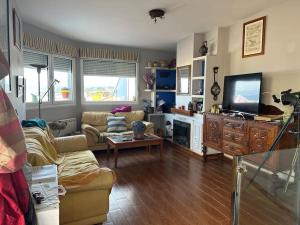 a living room with a couch and a tv at La ventana al mar in Luanco