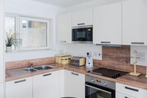 a kitchen with white cabinets and a sink and a window at The City Song in Rotherite in London