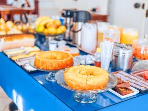 un buffet con pasteles y otros alimentos en una mesa azul en VELINN Pousada Mirante da Praia Grande, en Ilhabela