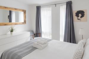 Un dormitorio con una cama blanca con toallas. en The City Song in Rotherite en Londres