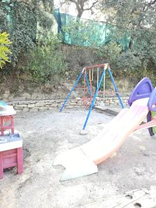 a playground with a slide and a swing set at La casita de madera Sijuela in Ronda