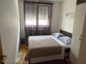 um pequeno quarto com uma cama e uma janela em Pia Apartment -SelfCheckIn-free parking em Zagreb