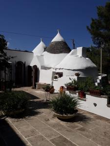 a white building with a roof with potted plants at Trullo Mauro MGG - Trullo Fragale in Martina Franca
