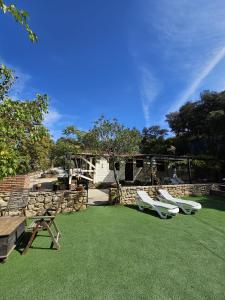 a backyard with two lawn chairs and a stone wall at La casita de madera Sijuela in Ronda