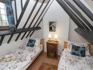 a attic bedroom with two beds and a mirror at Newbury Cottage in Bourton on the Water