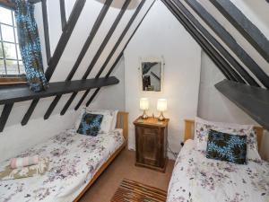 1 dormitorio en el ático con 2 camas y espejo en Newbury Cottage, en Bourton on the Water