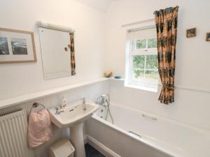 Un baño con lavabo, bañera y espejo. en Newbury Cottage, en Bourton on the Water 28 fotos más
