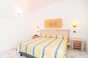 sypialnia z łóżkiem z żółtym i niebieskim kocem w paski w obiekcie Oriente Suites e Spa w mieście Ischia