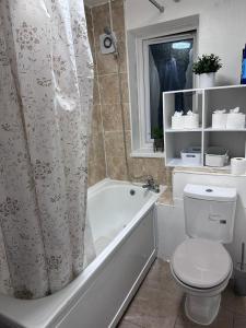 een badkamer met een bad, een toilet en een douchegordijn bij Haven 1 in Thamesmead